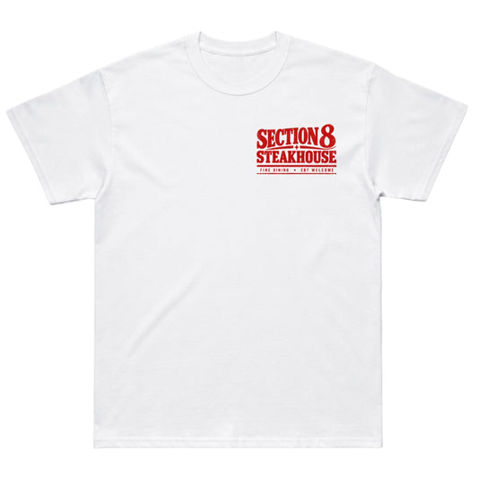 A white short-sleeve crewneck t-shirt with a red graphic print on the left chest reading 'SECTION 8 STEAKHOUSE' and 'JIM BEACH - EST. 1980'.