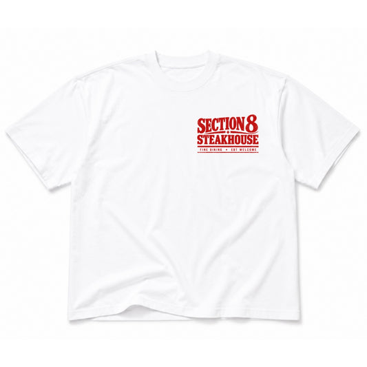 A white short-sleeve crewneck t-shirt featuring a red graphic print on the left chest that reads 'SECTION 8 STEAKHOUSE' with 'SAN ANTONIO - NEW MEXICO' printed underneath in smaller text.